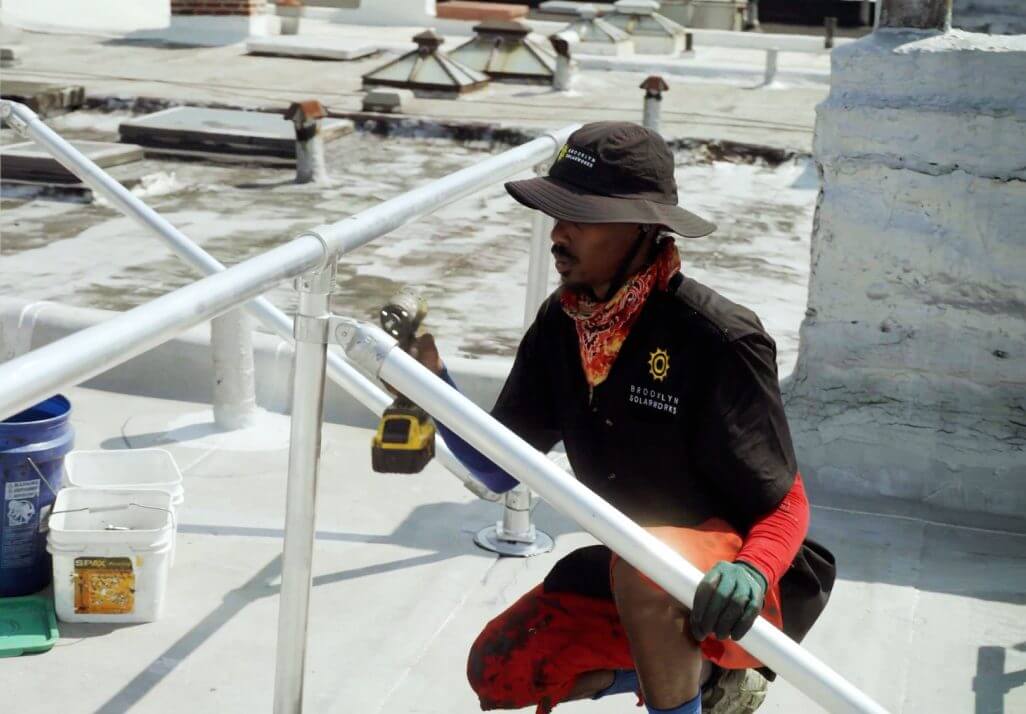 Brooklyn Solarworks installer on a roof drilling equipment