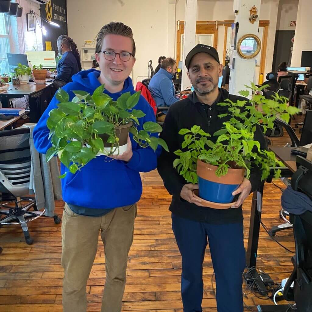Two men posing with their indoor grown office plants. Proud plant Dads.