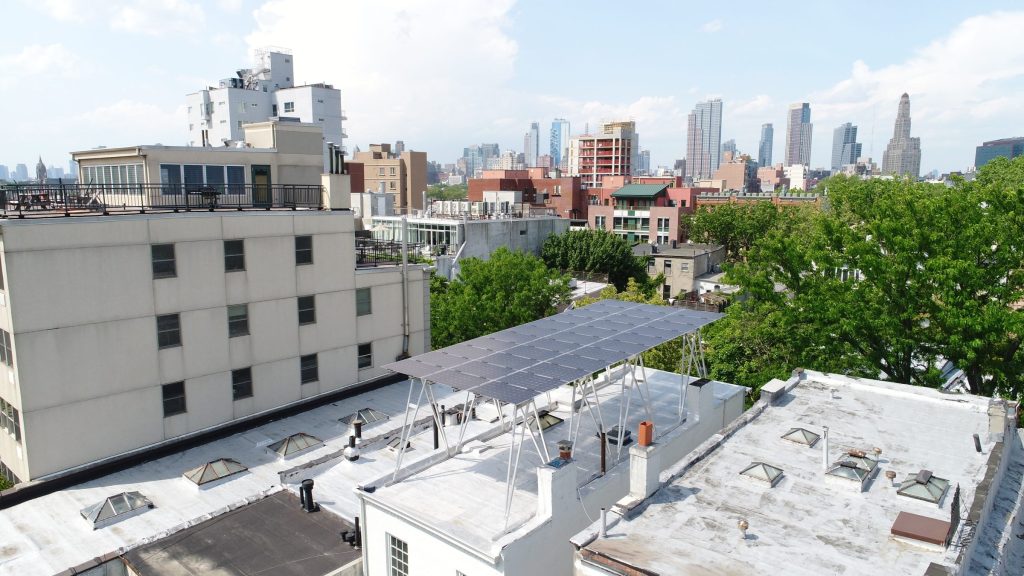 Solar canopy installed on a flat roof in Brooklyn with Manhattan skyline in background.