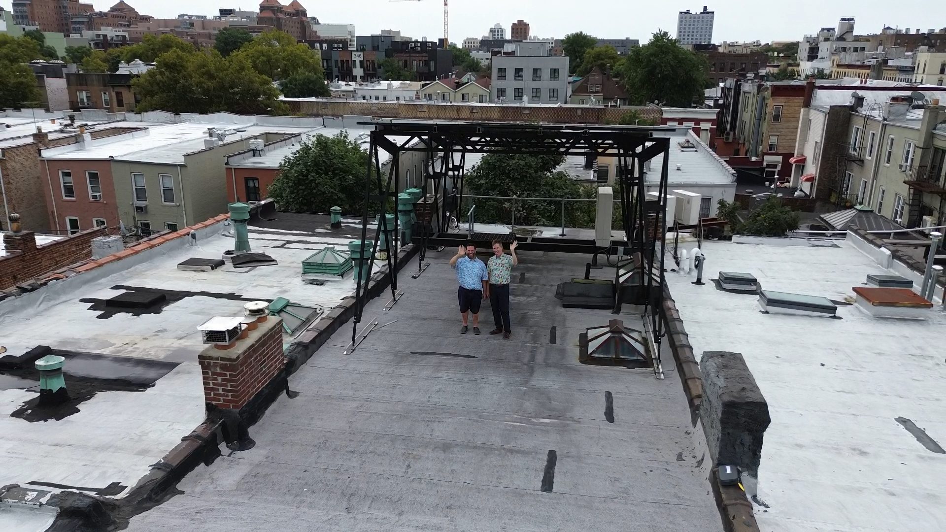 Brooklyn locals, Trevor and Gary, waving under their solar canopy in Prospect Lefferts Gardens.